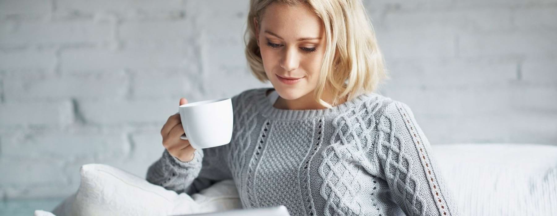 a woman sitting on a sofa drinking coffee